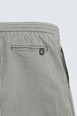 Bañador de hombre color verde claro con finas rayas blancas verticales (efecto seersucker). Tiene cintura elástica ajustable con cordón verde, bolsillos laterales y un bolsillo trasero de vivo.