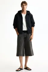 Campera rompevientos de nylon color negro, repelente al agua, con capucha ajustable con cordón, cierre frontal y bolsillos laterales. Cuenta con elásticos en los puños y forro interno.
