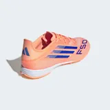 Championes de fútbol Adidas F50 League para pasto artificial, color naranja con tres franjas azules en el lateral y la inscripción "F50" en la puntera. Cuentan con mediasuela de EVA y suela de caucho con tacos bajos.