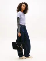 Cartera tipo tote de Tommy Jeans confeccionada en denim de algodón color negro. Presenta un diseño rectangular con asas superiores y una cadena metálica decorativa en el frente. Incluye el logo de la marca bordado en el centro.