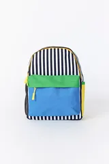Mochila con diseño combinado que presenta un patrón de rayas verticales blancas y negras en la parte superior, un bolsillo frontal con solapa verde y cuerpo azul, y laterales en color amarillo. Incluye cierres con tiradores amarillos.