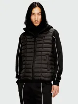 Chaleco acolchado negro con capucha, cierre frontal y diseño híbrido que combina paneles de nylon con mangas de tejido tipo buzo con detalles de líneas blancas.