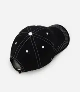 Gorra de sarga de algodón color negro con costuras decorativas en hilo blanco contrastante. Presenta visera curva, ojales bordados y ajuste posterior mediante hebilla metálica.