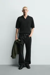 Polo de punto color negro con textura irregular, cuello solapa con abertura frontal, manga corta y acabados en rib, de corte relaxed fit.