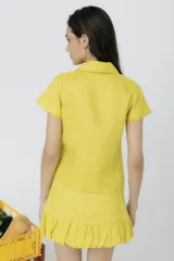 Top de lino color blanco, con cuello polo, cierre frontal parcial y mangas cortas. Presenta pespuntes a contratono.