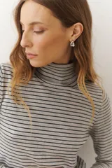 Rompeviento color beige con rayas horizontales finas en marrón, cuello alto y mangas largas.