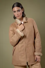 Campera de babylamb color beige con interior de piel sintética al tono. Presenta cierre frontal, capucha desmontable, bolsillos laterales, presillas ajustables en la cintura y cierres en los laterales del ruedo.