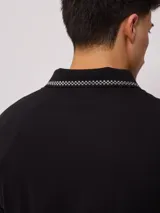 Remera polo blanca de corte regular, con cuello y mangas con ribete a cuadros en contraste. Presenta un pequeño logo bordado en el pecho.