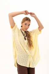 Camisa de corte oversize y mangas murciélago, confeccionada en tela con perforaciones tipo broderie. Presenta cuello mao, cierre frontal con botones y un diseño holgado y fluido.