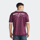 Camiseta de fútbol del Olympique de Marseille, color bordó con estampado geométrico en tonos oscuros. Presenta cuello polo blanco con detalles en negro, mangas cortas con borde blanco y logos estampados en el frente.