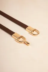 Cinturón fino marrón con hebilla dorada de abroche.