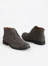 Bota corta tipo botineta de cuero negro con textura granulada, cierre mediante cordones y suela plana de goma.