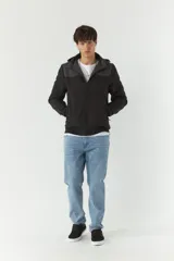 Campera softshell negra con capucha removible y bolsillos con cierre.