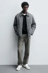 Zapatilla deportiva de estilo retro, color negro, con parte superior fabricada en combinación de piezas de cuero liso y gamuza perforada. Presenta una suela de goma en color marrón oscuro o ahumado en contraste.