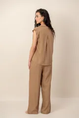 Conjunto compuesto por una blusa sin mangas con cuello camisero, bolsillos frontales y cierre de botones, y un pantalón largo de corte recto y holgado, ambos confeccionados en tejido texturizado de color marrón.