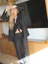 Pantalón de vestir negro con finas rayas verticales blancas, de corte palazzo y tiro alto.