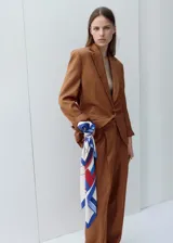 Pantalón de vestir de corte recto y tiro medio, color marrón, con pinzas frontales y bolsillos laterales.