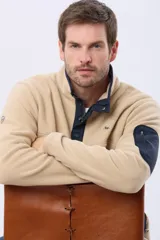 Buzo de abrigo confeccionado en tejido polar térmico, con cuello alto y cierre frontal parcial con broches. Presenta bolsillos laterales con cierre y un bolsillo adicional con cierre en la manga izquierda.