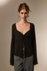 Top de manga larga color negro, con escote cuadrado y detalle de nudo frontal que genera una abertura central. Confeccionado en tejido de poliéster con ajuste al cuerpo.