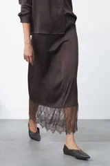 Falda midi negra de caída fluida con cintura elastizada y un amplio detalle de encaje negro en el bajo.