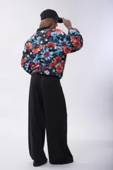 Campera bomber acolchada con cierre frontal, diseño estampado floral multicolor sobre base negra, cuello, puños y ruedo elásticos.
