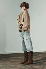 Jersey de punto liso con diseño oversize, cuello redondo y manga larga con puños acanalados.