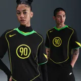 Camiseta Nike Total 90 Energy de color negro, con detalles en amarillo flúor y verde, de manga corta y cuello en V. Presenta un diseño inspirado en los años 2000 con el número 90 impreso en el centro del pecho y ribetes curvados en contraste.