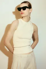 Top de punto color crema, sin mangas, con cuello redondo y corte ajustado.