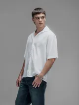 Camisa blanca de manga corta, con cuello clásico y cierre de botones frontal.