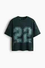 Remera de malla color verde oscuro, de corte oversized y manga corta, con cuello redondo y gran estampado frontal con el número 22 en tono celeste.