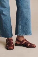 Sandalia tipo cangrejera de cuero lavado color marrón rojizo, con diseño de tiras entrelazadas, puntera cerrada y ajuste mediante correa con hebilla metálica en el tobillo.