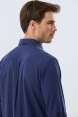 Camisa de lino de manga larga en color beige, con cuello camisero, cierre frontal de botones y un bolsillo ojal en el pecho.