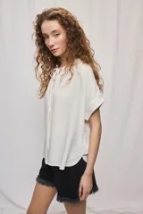 Camisa de manga corta color celeste, confeccionada en viscosa fluida, con silueta amplia y escote redondo con frunces y lazo para anudar.