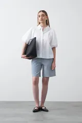 Bermuda de denim azul claro con rayas verticales blancas, de corte relajado y largo hasta la rodilla. Presenta pespuntes a contratono.