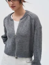 Cardigan de punto color gris, con cierre frontal completo, cuello redondo y diseño de manga larga con hombros caídos.