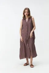 Vestido largo sin mangas de color celeste, con cuello camisero, cierre frontal con botones y bolsillos laterales.