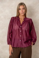 Camisa de organza blanca con cuello mao, diseño de manga larga tipo murciélago y cierre frontal con botones. Presenta un corte holgado y fluido.
