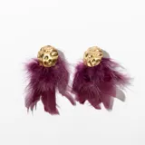 Aros colgantes con base circular dorada y flecos de plumas color mostaza.