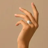 Anillo de plata con acabado satinado, diseño envolvente con una banda ancha que se cruza sobre sí misma.