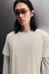 Camiseta de entrenamiento regular fit color beige, confeccionada en combinación de tejidos técnicos ligeros y elásticos con tecnología Quick Dry nivel 2. Presenta cuello redondo, manga corta, acabados con costuras planas y termofijadas, y detalle de logo estampado en el bajo.