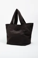 Bolso tipo shopper de color beige, con diseño amplio y doble asa de hombro. Presenta un detalle frontal de bordados coloridos con hilos colgantes que forman un diseño artístico.