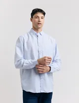 Camisa celeste con pequeños lunares blancos, de manga larga, con cuello abotonado y bolsillo en el pecho.