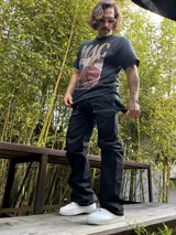 Pantalón negro de gabardina, corte ancho tipo carpenter, con costuras blancas contrastantes.