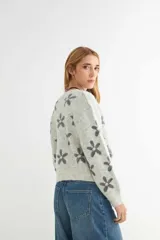 Cardigan de punto con estampado de flores, cuello redondo y cierre frontal con botones. Presenta un diseño de corte holgado con puños y ruedo acanalados.