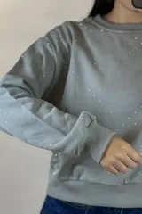 Buzo de cuello redondo y manga larga, color negro, con diseño de pequeños puntos brillantes distribuidos por toda la prenda. Presenta puños y ruedo acanalados.