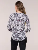 Blusa de gasa estampada de la marca Zac & Rachel, con diseño floral en tonos azul, celeste y verde sobre base blanca. Presenta escote en V con abertura y botones frontales, y mangas largas de largo regulable con presilla.