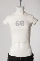 Baby tee de calce al cuerpo y manga corta, con cuello redondo y diseño con tachas frontales.