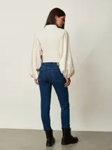 Jean chupín negro de tiro alto, confeccionado en denim con cinco bolsillos tradicionales y cierre frontal con botón y cremallera.