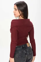 Sweater corto de tejido acanalado en color bordó, con cuello tipo off-shoulder solapado y cierre frontal completo con cremallera.