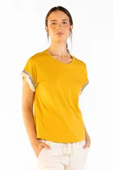 Remera de manga corta color mostaza, confeccionada en 100% algodón, con cuello redondo y detalles de flecos y guardas geométricas en las mangas.